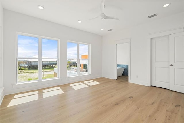 2626 Bridgeview Dr, Dauphin Island, AL 36528 - unfurnished bedroom featuring multiple windows, light wood finished floors, recessed lighting, ensuite bath, and ceiling fan