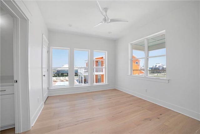 empty room with light wood-type flooring, baseboards, and a ceiling fan