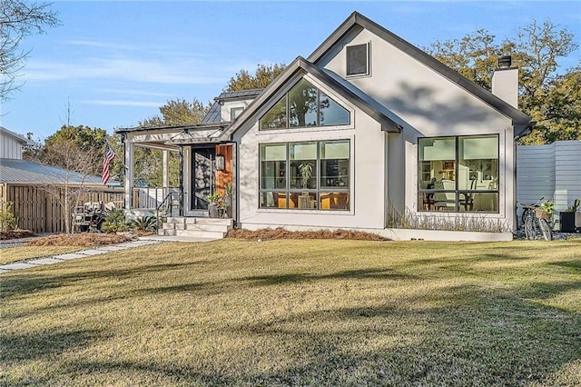 exterior space featuring a chimney, fence, and a front lawn