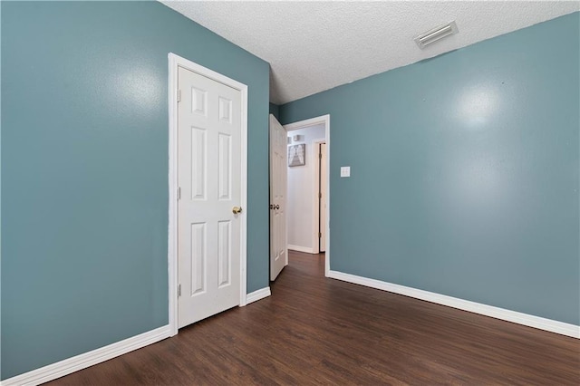 unfurnished bedroom with dark hardwood / wood-style flooring and a textured ceiling