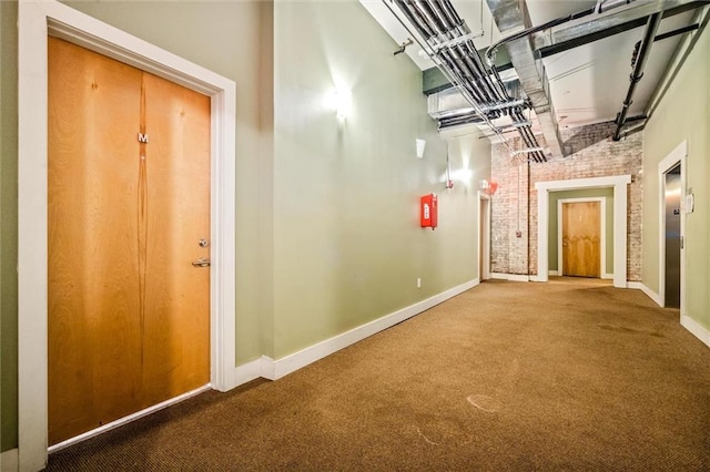 hallway featuring brick wall and carpet