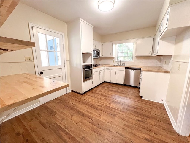 kitchen with sink, white cabinetry, stainless steel appliances, light wood-type flooring, and decorative backsplash