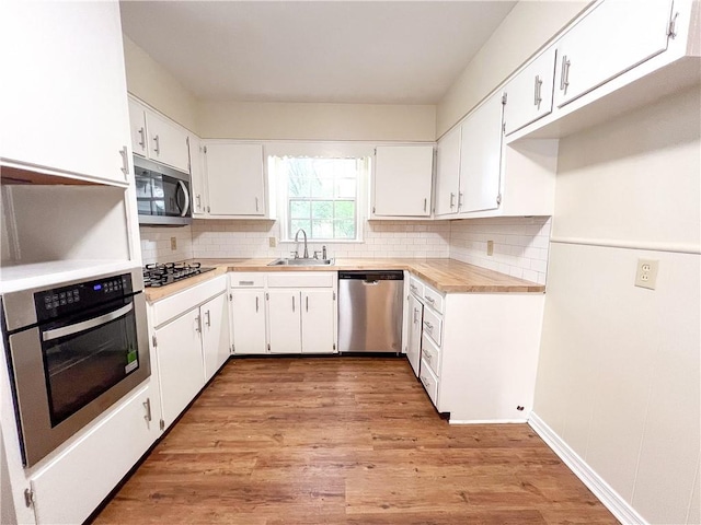 kitchen featuring appliances with stainless steel finishes, white cabinetry, sink, and light hardwood / wood-style flooring