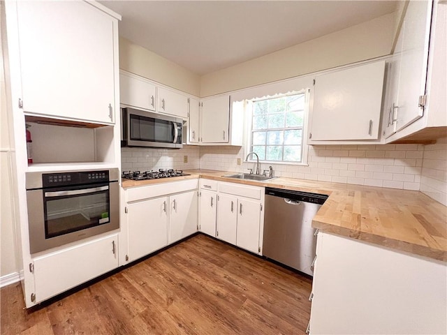 kitchen featuring stainless steel appliances, white cabinetry, light wood-type flooring, and sink