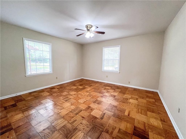 unfurnished room with ceiling fan, parquet flooring, and a healthy amount of sunlight