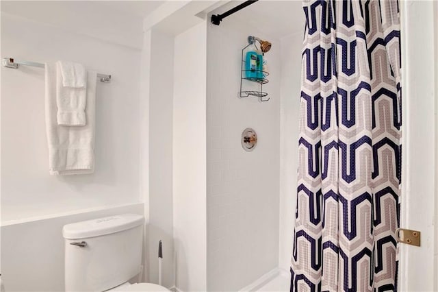 bathroom featuring toilet and curtained shower