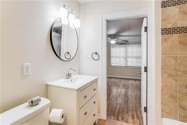 bathroom with ceiling fan, toilet, vanity, a tub to relax in, and hardwood / wood-style flooring