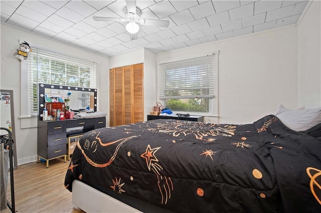 bedroom with crown molding, ceiling fan, light wood-type flooring, and a closet