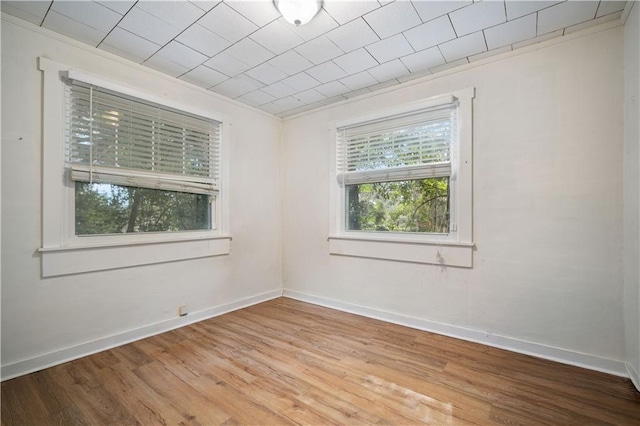 empty room with hardwood / wood-style floors and crown molding