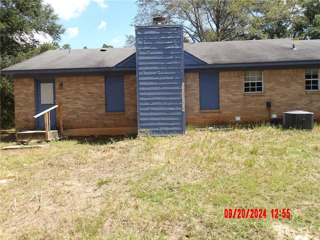 back of house with cooling unit and a yard