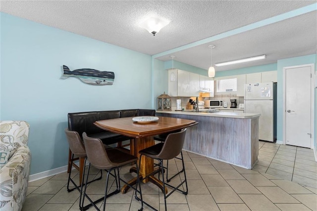 633 Beach Blvd Unit 205, Gulf Shores, AL 36542 - dining space with light tile patterned flooring, a textured ceiling, and baseboards