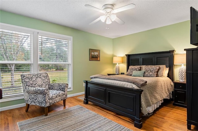 bedroom featuring ceiling fan, light hardwood / wood-style flooring, and a textured ceiling