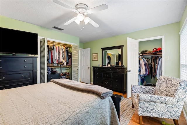 bedroom with ceiling fan, light wood-type flooring, and multiple closets