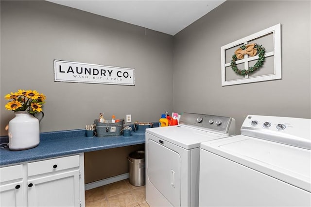 washroom with cabinets, washing machine and dryer, and light tile patterned floors