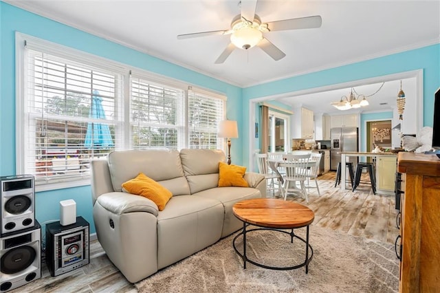 living room featuring plenty of natural light, ceiling fan with notable chandelier, and light hardwood / wood-style flooring