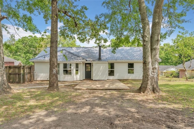 rear view of house featuring fence, a patio area, and metal roof