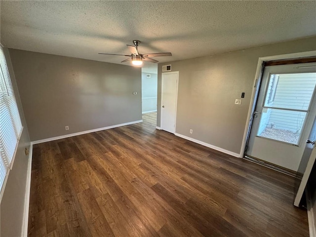 empty room featuring a textured ceiling, ceiling fan, and dark wood-type flooring