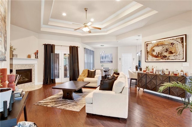 living room with ornamental molding, a high end fireplace, dark hardwood / wood-style flooring, and a tray ceiling