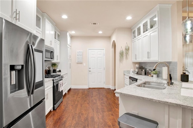 kitchen featuring sink, hanging light fixtures, stainless steel appliances, light stone countertops, and white cabinets