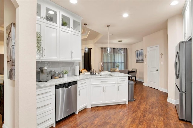 kitchen with light stone countertops, kitchen peninsula, white cabinets, and appliances with stainless steel finishes