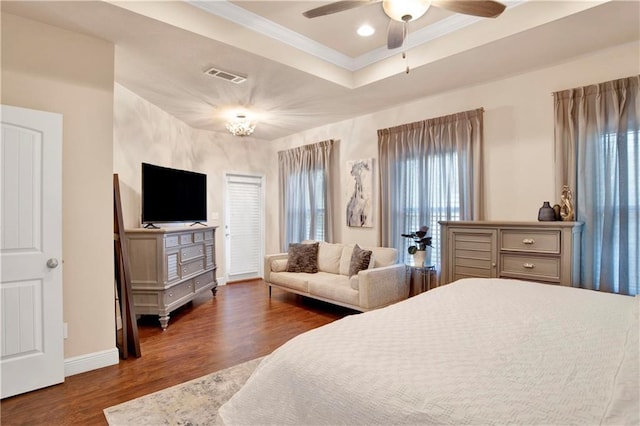 bedroom with crown molding, dark wood-type flooring, and a tray ceiling