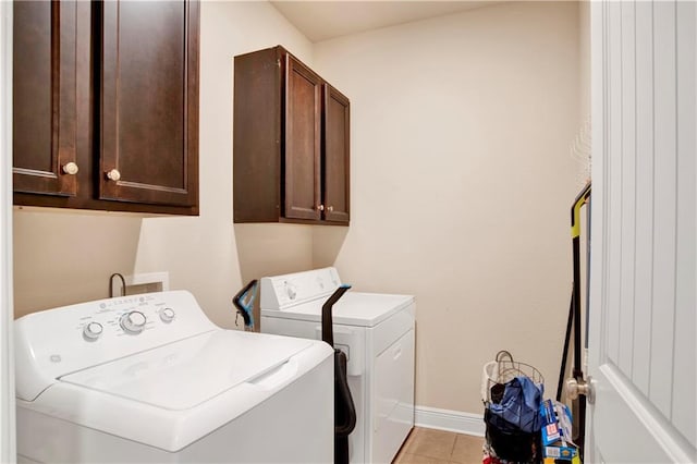 washroom featuring cabinets, light tile patterned flooring, and washer and clothes dryer