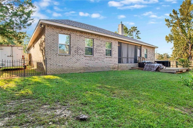 back of property featuring a jacuzzi and a lawn