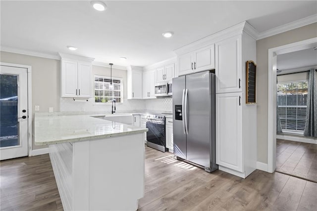 kitchen with light stone countertops, stainless steel appliances, plenty of natural light, pendant lighting, and white cabinets