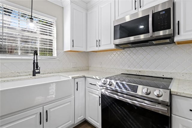 kitchen featuring hanging light fixtures, white cabinets, and stainless steel appliances