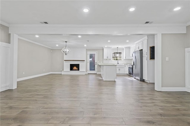 unfurnished living room featuring crown molding, sink, and light hardwood / wood-style floors