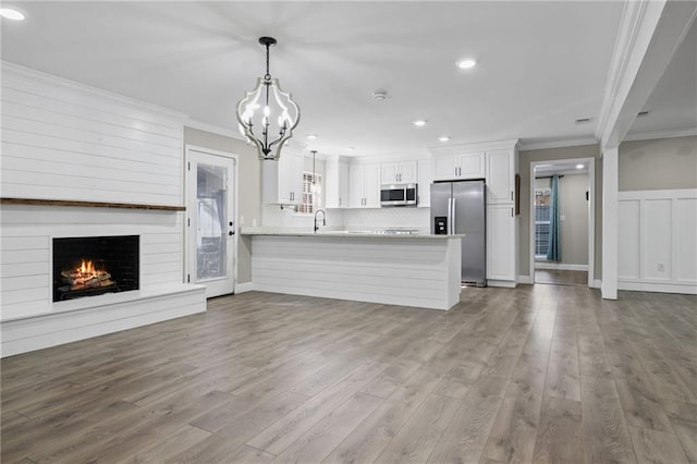 unfurnished living room featuring sink, light hardwood / wood-style flooring, crown molding, and a notable chandelier