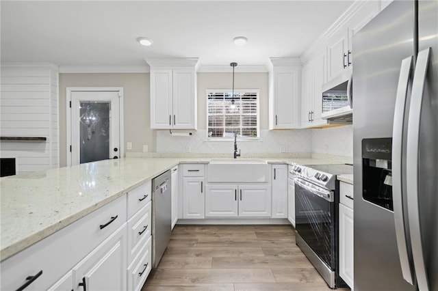 kitchen with white cabinetry, sink, stainless steel appliances, crown molding, and pendant lighting