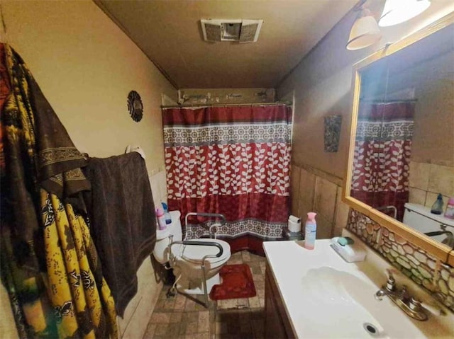 bathroom featuring vanity, toilet, tile walls, and walk in shower