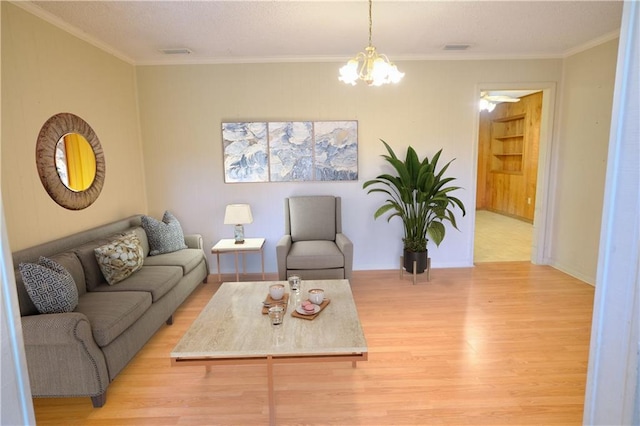 living room with a notable chandelier, visible vents, crown molding, and light wood-style floors