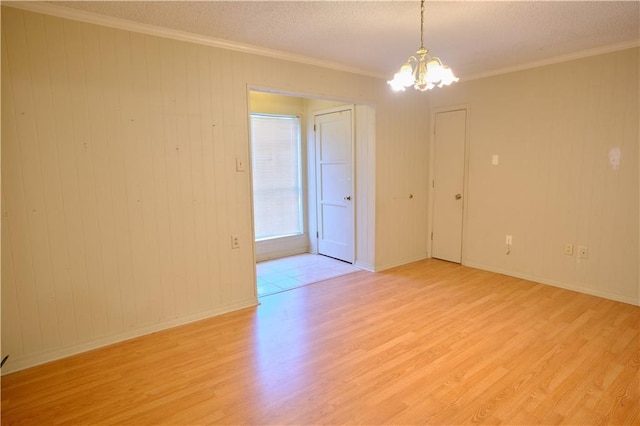 spare room featuring a notable chandelier, light hardwood / wood-style floors, and crown molding