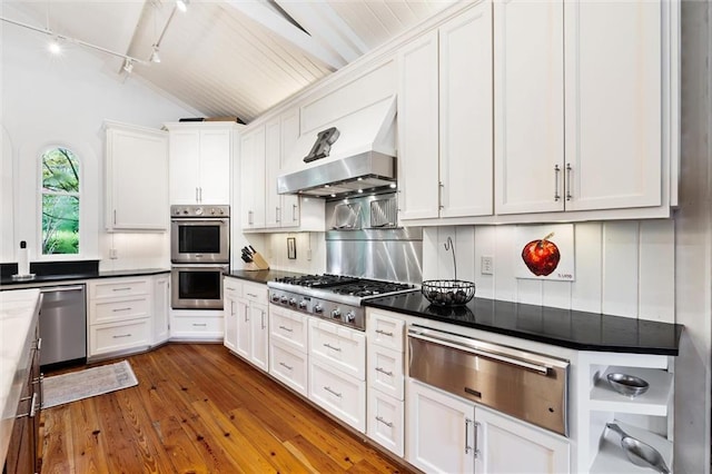 kitchen with wall chimney range hood, wood-type flooring, stainless steel appliances, and white cabinets