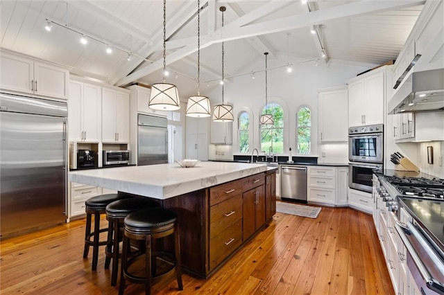 kitchen with white cabinetry, appliances with stainless steel finishes, a center island, and hanging light fixtures