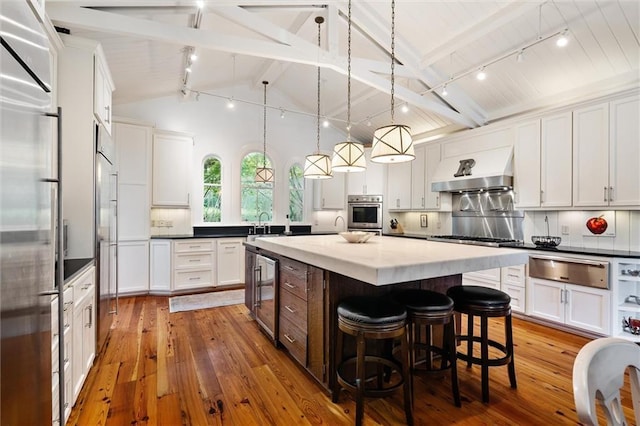 kitchen featuring a kitchen island, wood-type flooring, wine cooler, hanging light fixtures, and custom range hood