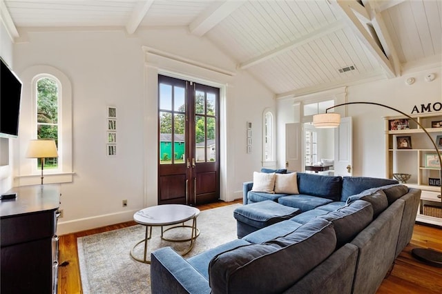 living room with lofted ceiling with beams, hardwood / wood-style floors, and french doors