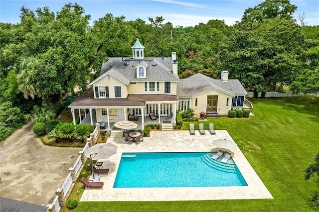 back of house featuring a fenced in pool, a lawn, and a patio