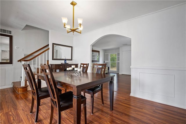 dining space featuring arched walkways, visible vents, wood finished floors, a decorative wall, and a notable chandelier