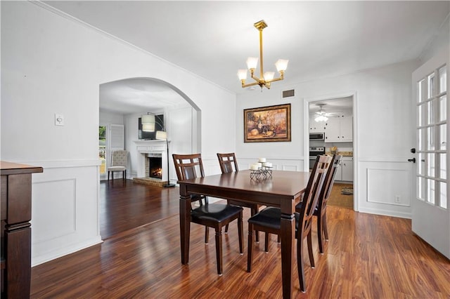 dining area with a brick fireplace, visible vents, dark wood finished floors, and a decorative wall