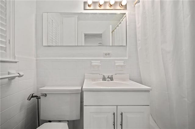 full bath featuring toilet, vanity, and tile walls