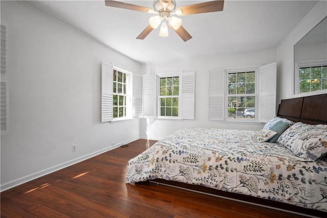 bedroom featuring a ceiling fan, multiple windows, baseboards, and wood finished floors