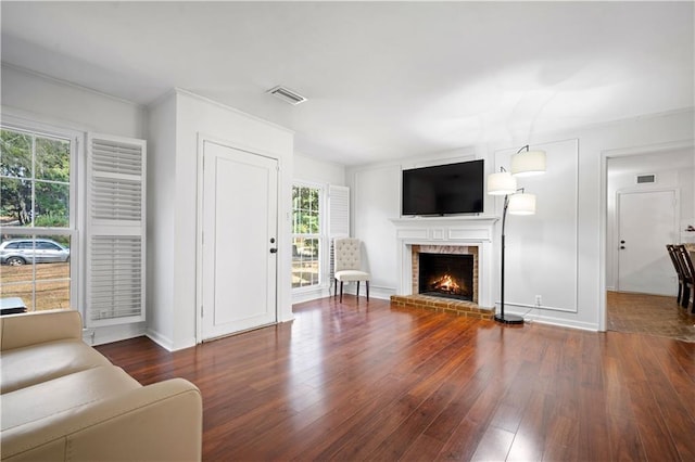 living area featuring a fireplace, visible vents, and wood finished floors