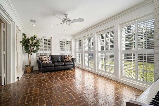 sunroom featuring a wealth of natural light, visible vents, and a ceiling fan