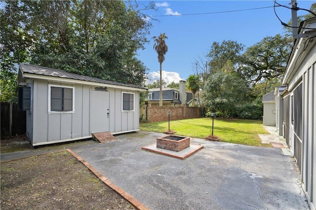 exterior space with an outdoor fire pit, fence, and an outdoor structure