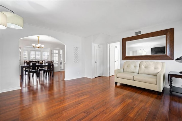 living room with wood-type flooring, visible vents, arched walkways, and a notable chandelier