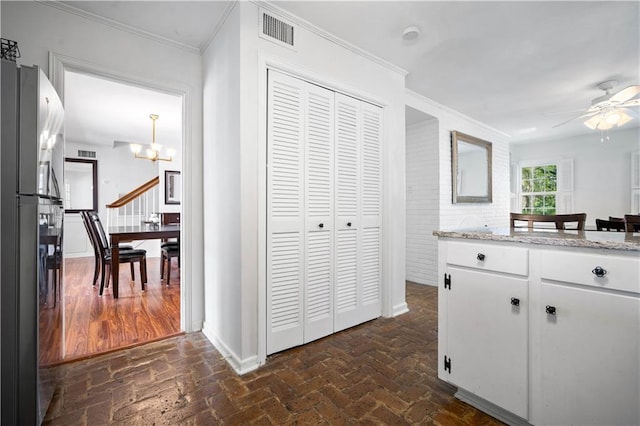 kitchen featuring visible vents, brick floor, freestanding refrigerator, and crown molding