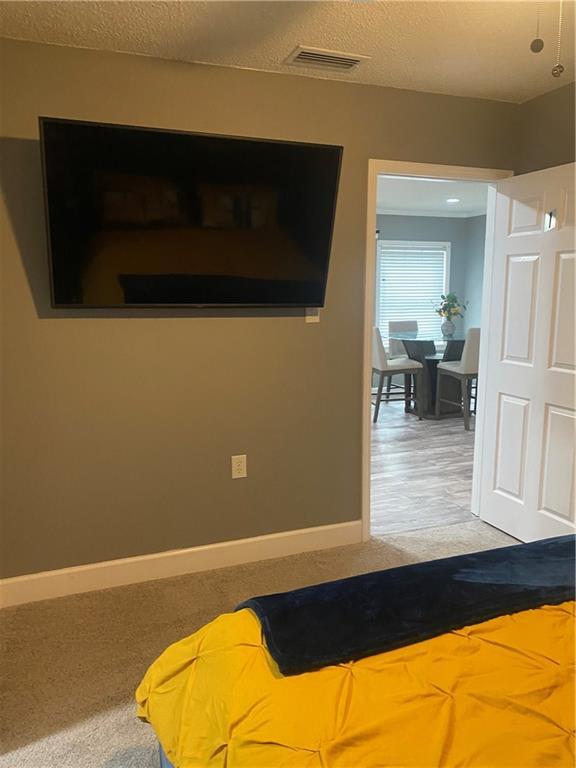 unfurnished bedroom with light carpet, a textured ceiling, visible vents, and baseboards